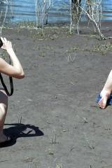 Girl taking a picture of another on all fours.