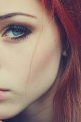 Red hair, blue eyes, nose piercing, intense look.